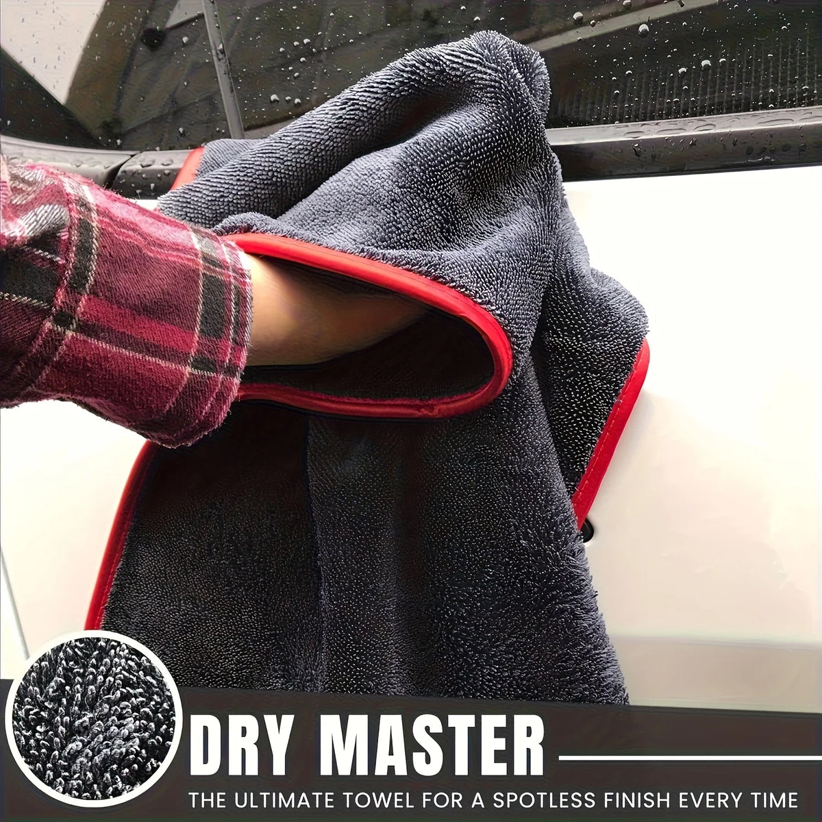 A dark gray microfiber drying towel is draped over a vehicle, showing its texture and red trim.