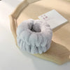 A light gray microfiber wrist sweatband and scrunchies are displayed on a beige tray next to a white card.