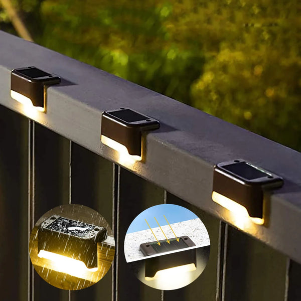 Primer plano de luces LED solares para escalones montadas en una barandilla, iluminando un sendero exterior.