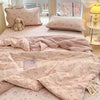 A pink cartoon pattern kids lightweight summer quilt displayed on a bed with matching pillows and bedding.