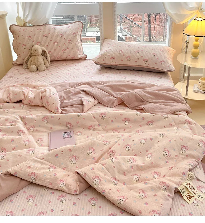 A pink cartoon pattern kids lightweight summer quilt displayed on a bed with matching pillows and bedding.