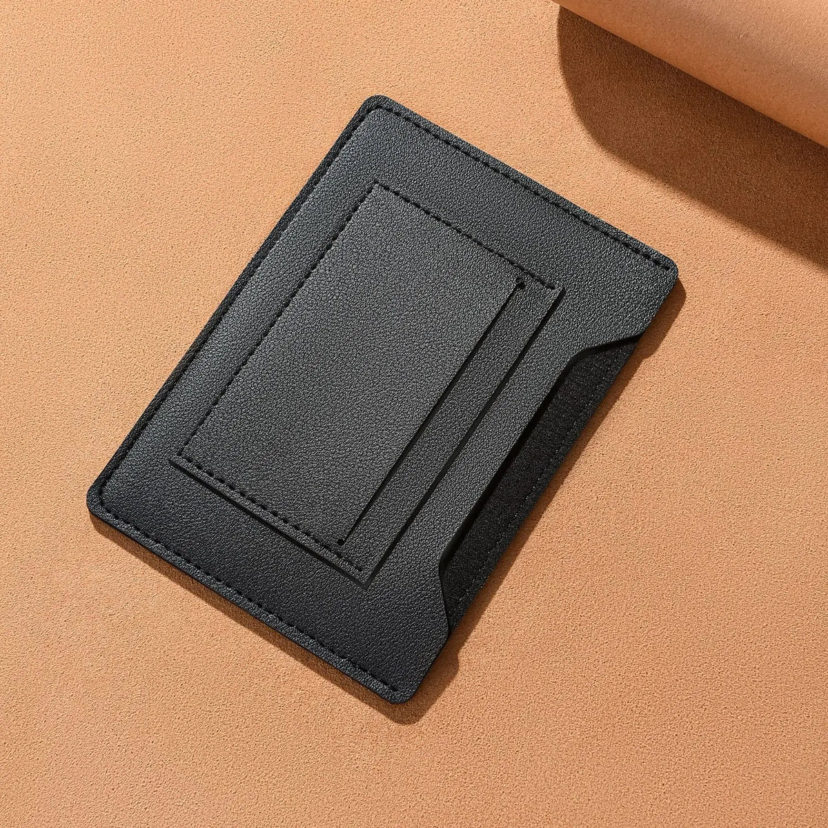 A black ultra-thin passport holder with card slots lying on a beige surface.