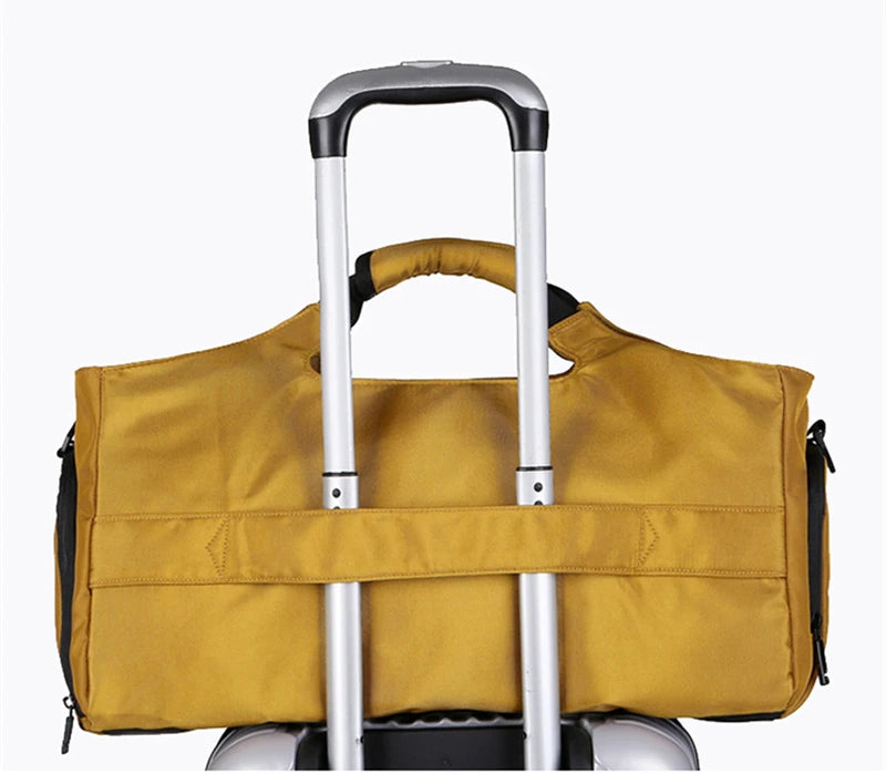A tan duffel bag with a black trim and a shoe pocket is shown resting on a silver rolling suitcase.