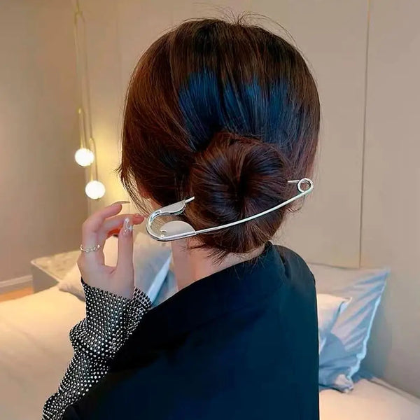 Eine Frau benutzt strapazierfähige Metall-Haarspangen, um ihr dunkles Haar zu stylen, von hinten gesehen.