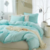 Light blue microfiber duvet cover set with pom tassels on a bed
