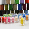 A collection of 64 colored sewing threads in spools arranged in rows.