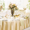 Elegant round satin tablecloth in champagne color set for weddings and parties.