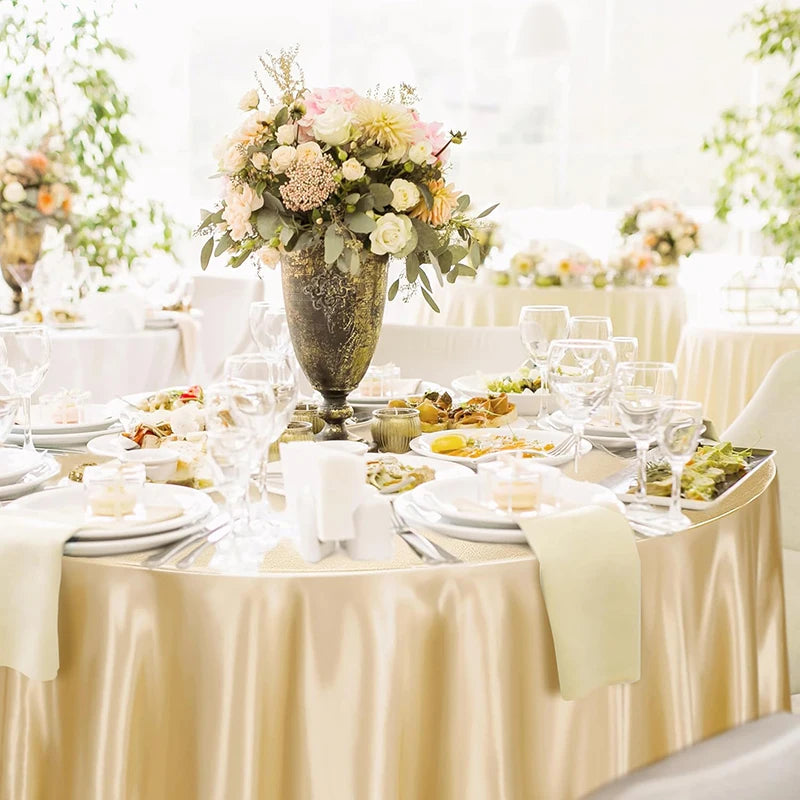 Elegant round satin tablecloth in champagne color set for weddings and parties.