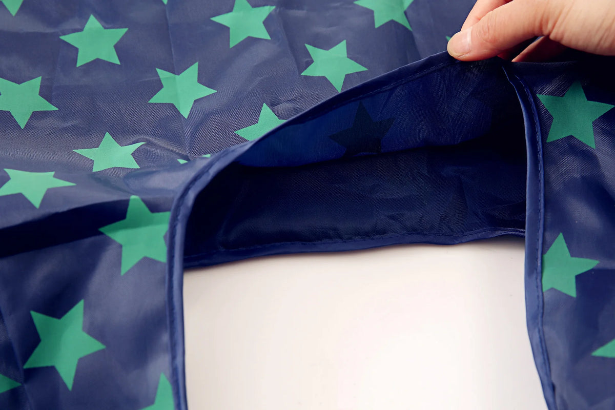 A dark blue foldable eco-friendly shopping bag with green stars is shown being folded.