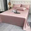 A pink luxury bamboo flat sheet is neatly folded on a bed with matching pillows and elegant bedside decor.