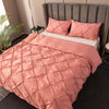 A pink 3D pinch pleated duvet cover set displayed on a bed with gray upholstered headboard and pillows.