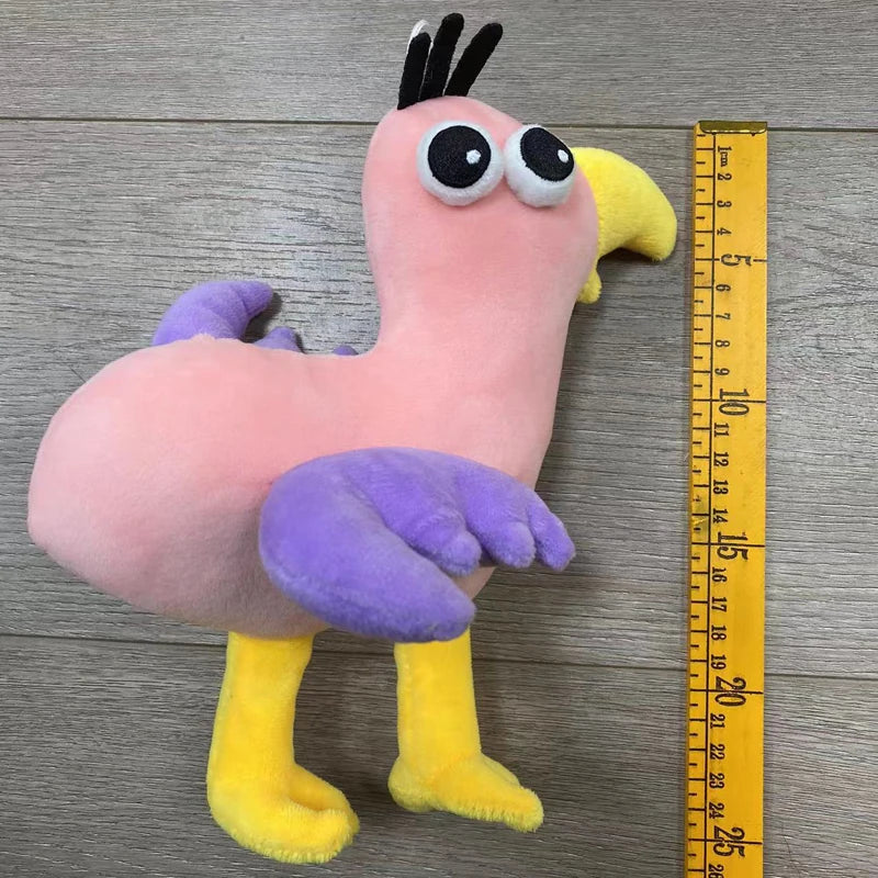 A pink and yellow plush toy of an Opila bird with large eyes and purple wings standing on a wooden surface.