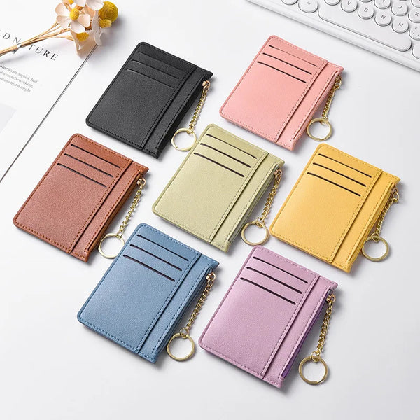 A collection of five slim zippered card wallets in various pastel shades including pink, yellow, green, and blue, displayed o
