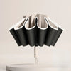 A black fully automatic reverse-folding windproof umbrella with white accents is displayed on a light surface.