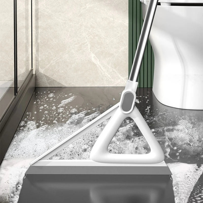 A white silicone squeegee broom is shown cleaning a floor surface with water and foam.