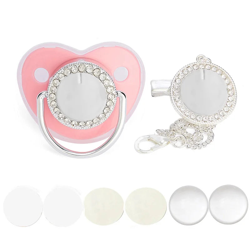 A sparkling rhinestone pacifier with a clip and a pink silicone holder is shown next to several white silicone pacifier tips.