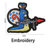 Embroidery of a blue dinosaur with a circular design and a red-tipped tail on a black background.