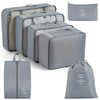 A set of gray travel packing cubes and a matching drawstring bag for organizing belongings
