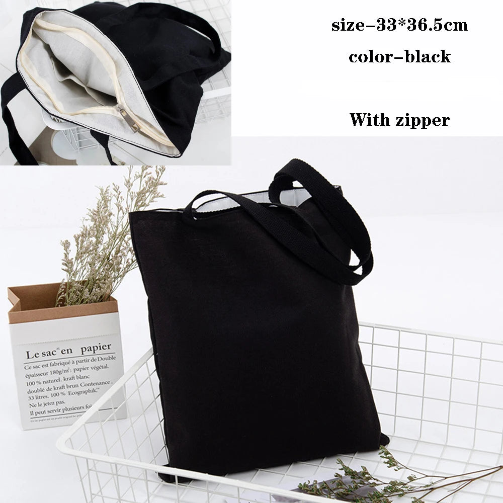 Black foldable canvas tote bag with a zipper shown next to a box of paper.