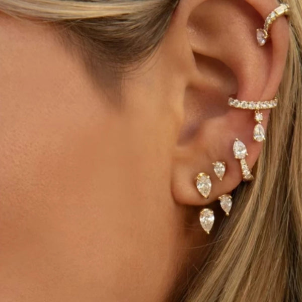 Primer plano de la oreja de una mujer mostrando delicados aretes de gotas de acero inoxidable.