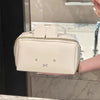 A beige Miffy cartoon rabbit cosmetic storage bag with a zipper is held in a hand in a bathroom setting.