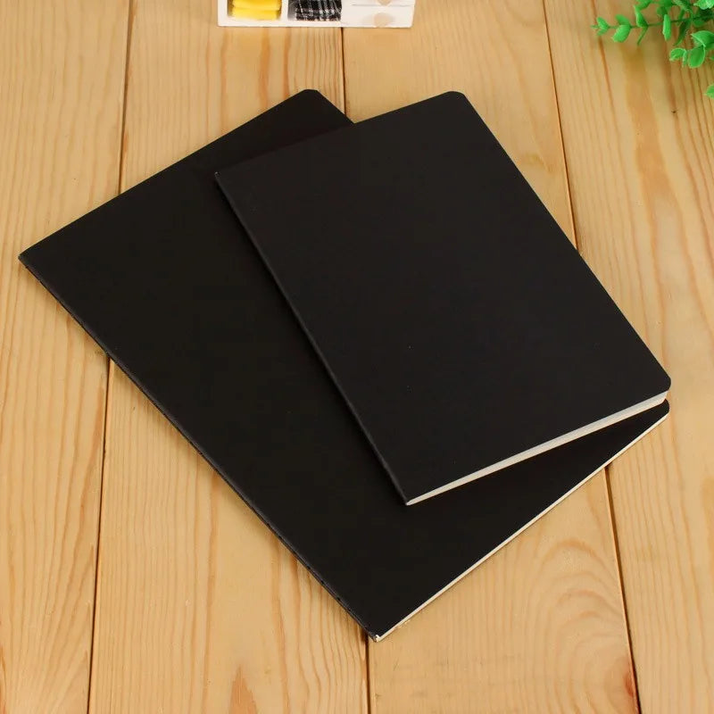 A black A6 kraft paper blank notebook lying on a light wooden surface.