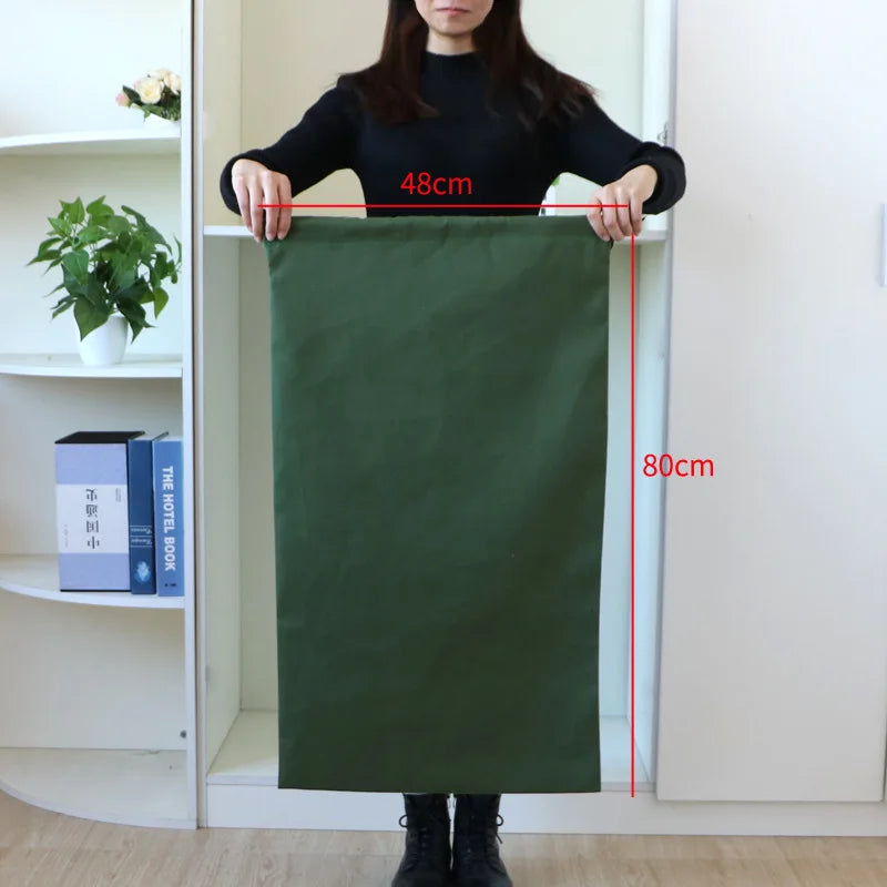 A dark olive green heavy-duty canvas laundry bag hanging on a door, showing its dimensions.