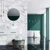 A modern bathroom vanity with a white vessel sink and marble-patterned wall tiles in a contemporary interior.