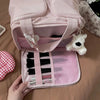 A pink cosmetic travel organizer bag with a zippered compartment and an open section displaying makeup brushes and a white be