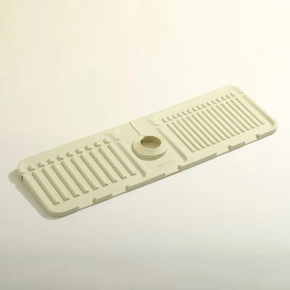 A beige silicone faucet draining mat with raised ridges and a central drain hole.