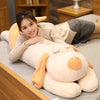 A woman is smiling while lying on a soft, light-colored dog plush pillow.
