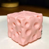 Pinkes, weiches Jumbo-Käse-Knet-Spielzeug-Würfel auf weißer Fläche.