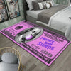 Una alfombra antideslizante decorativa rosa con estampado de billetes sobre un suelo de madera junto a una cama.
