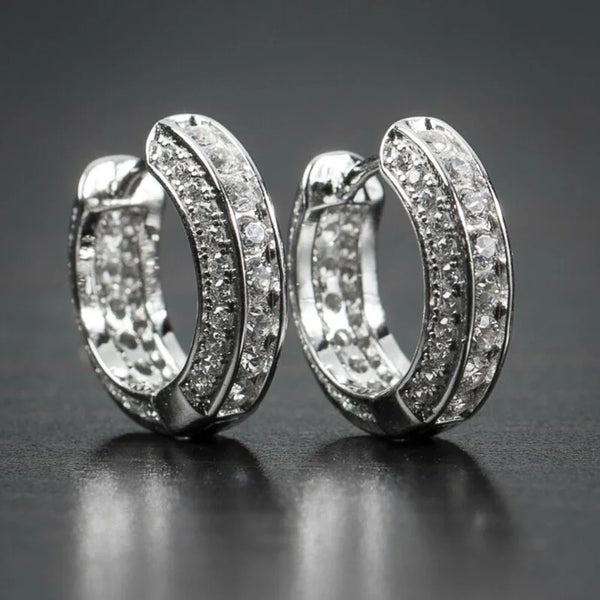 Une paire de boucles d'oreilles en anneau argentées incrustées de cristaux clairs et de zircon cubique.