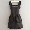 A black Korean style cotton kitchen apron with adjustable neck strap hanging on a hanger.