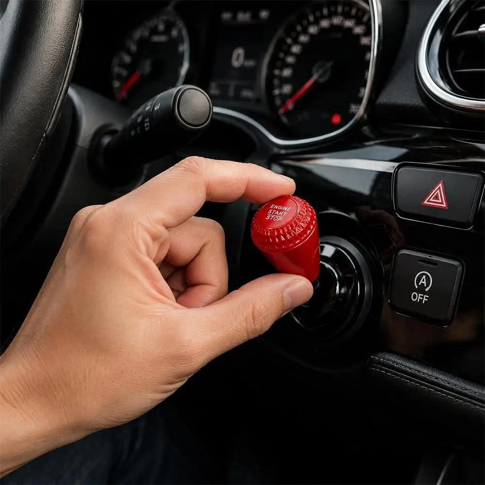A hand is pressing a red engine start button cover on a car dashboard control panel.