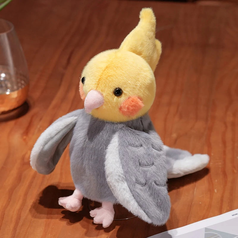 A fluffy yellow and gray plush parrot hand puppet toy standing on a wooden surface.