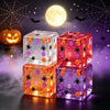 Cuatro juguetes antiestrés en forma de cubo brillantes con temática de Halloween como arañas y calabazas contra un fondo oscu