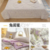 A purple and white patterned quilt is displayed on a bed with light curtains.