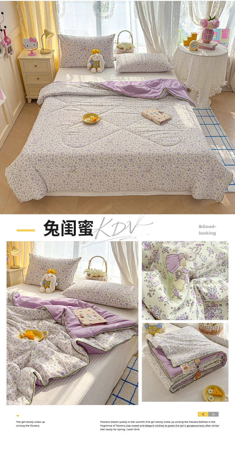 A purple and white patterned quilt is displayed on a bed with light curtains.