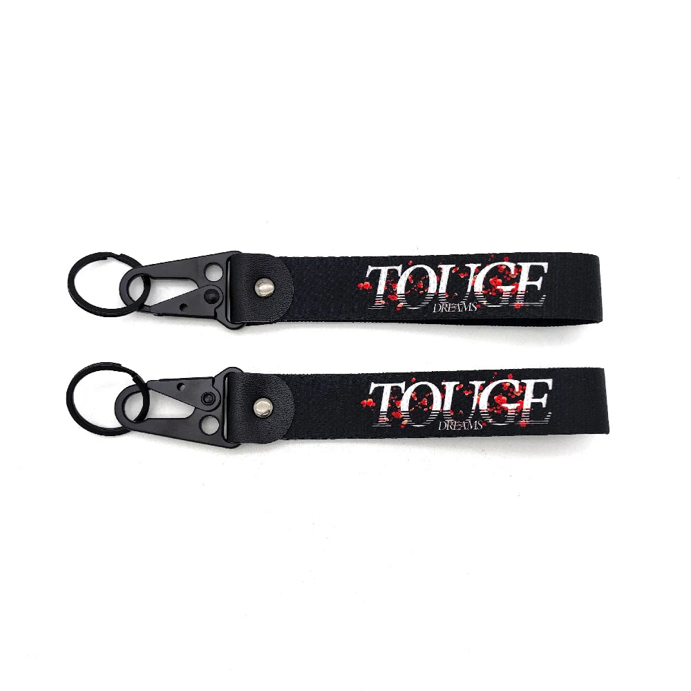 Black leather keychain with red text spelling TOUGE DREAMS