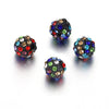 Four dark, round beads encrusted with various colored crystals are displayed on a white surface.