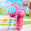 A pink automatic bubble rocket blaster toy is shown spraying bubbles outdoors on a green surface.