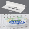 A white desktop pegboard organizer with shelves and hooks is shown in a close-up view.