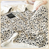 A beige leopard print plush jacquard throw blanket draped over a person in bed.