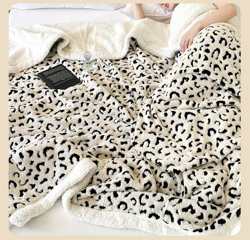 A beige leopard print plush jacquard throw blanket draped over a person in bed.