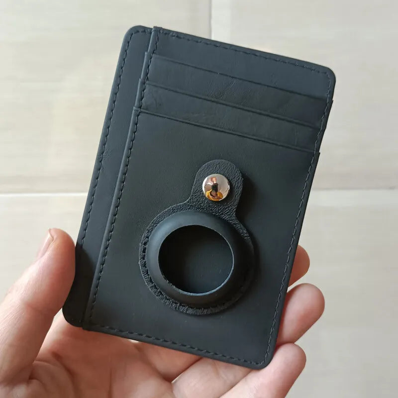 Una cartera delgada de cuero negro con una ranura circular para un AirTag sostenida en una mano.
