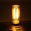 A glass accent LED night light with two bright filaments is placed on a dark surface.