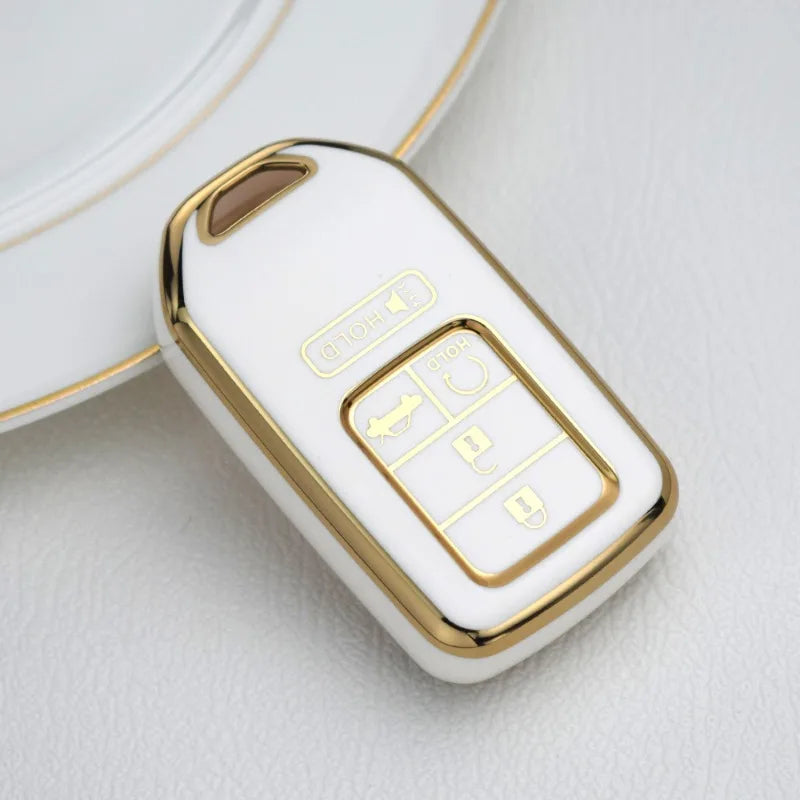 A white and gold TPU protective key case for a Honda vehicle, shown in a close-up view.