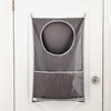 A gray laundry storage bag with a circular opening and a zippered bottom is hanging on a white door.